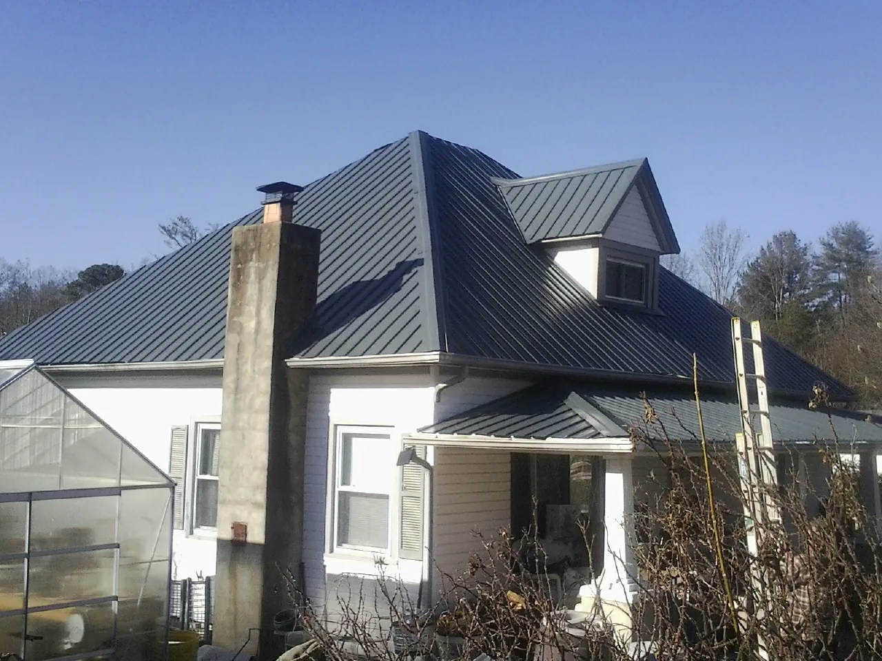 Dark blue standing seam metal roof on a white farmhouse with dormer — Slate & Tile Roof Repair by Roofing Brothers in Star Junction