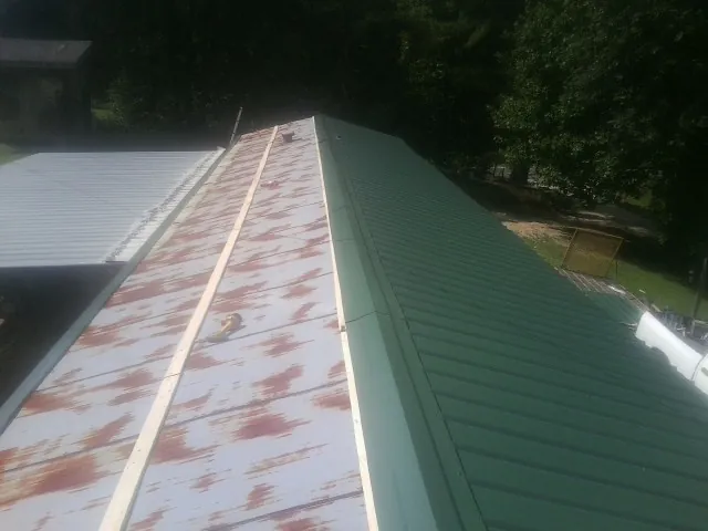 Old rusted panels beside newly installed green metal roofing — Wind Damage Roof Repair by Roofing Brothers in Star Junction