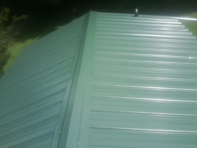 New green metal panels meeting at the ridge of a roof — Flat Roof Repair work by our crew in Star Junction