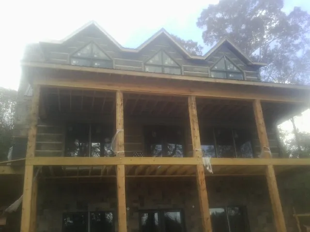 Dormers and porch framing on a large log home under construction — Roof Coating work by our crew in Star Junction