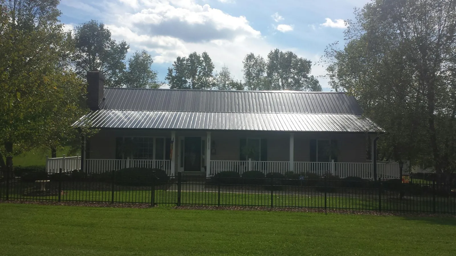 Gray metal roof on a brick ranch with a full width front porch — Gutter Guard Installation work by our crew in Star Junction
