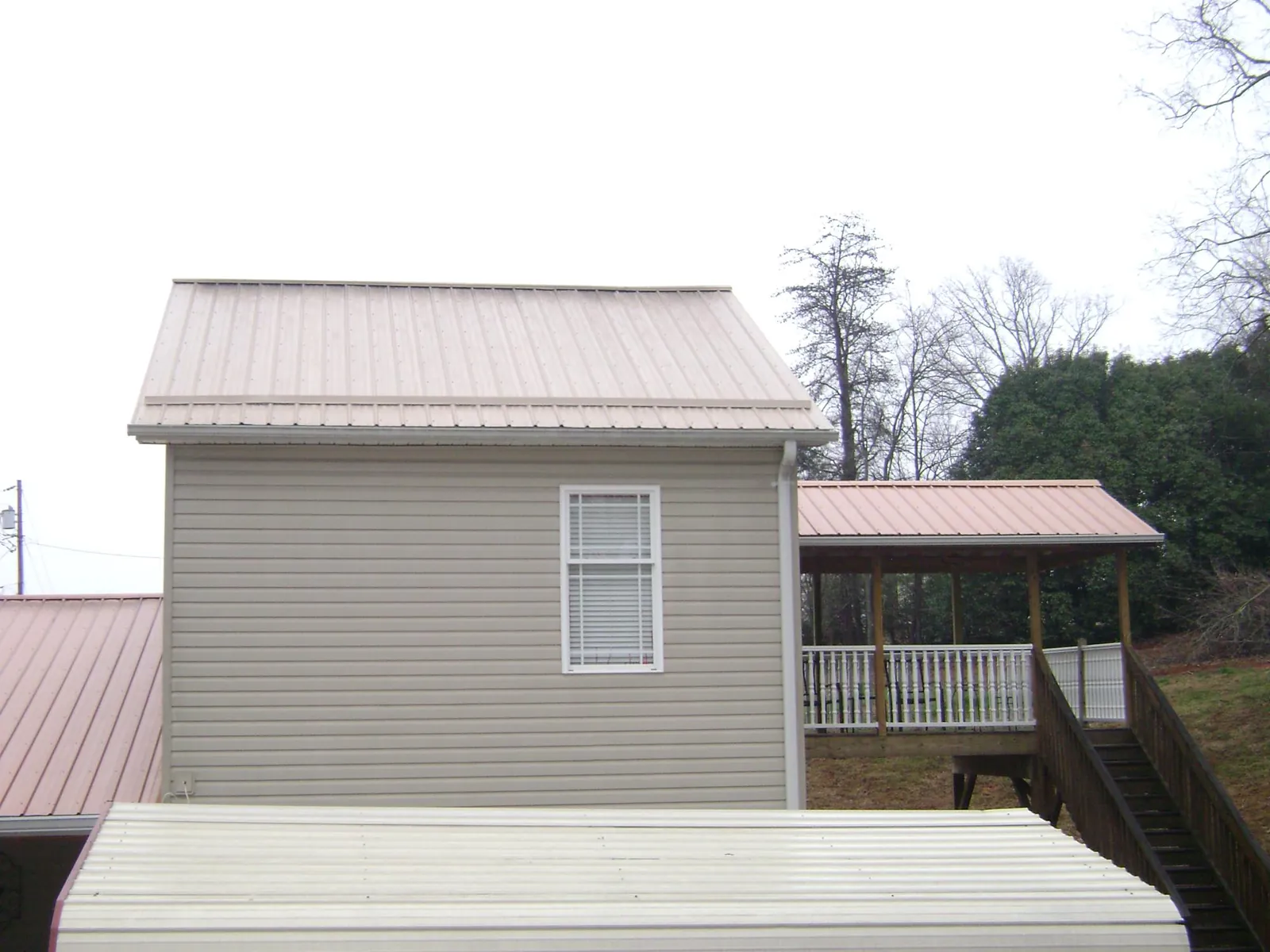 Tan metal roofs on a two story addition and attached porch, from a Roof Replacement job in Star Junction