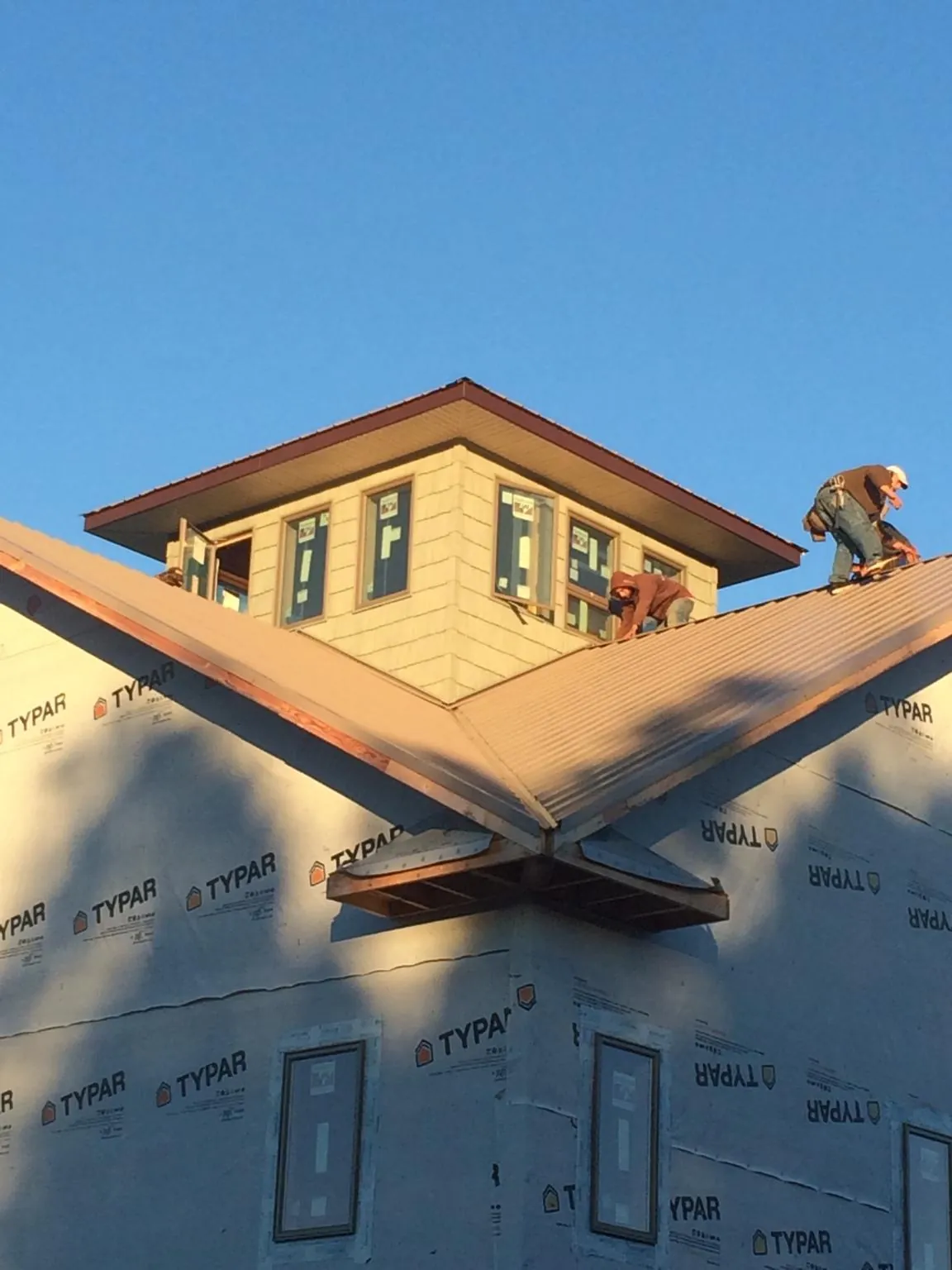 Roofers working around a rooftop cupola on a new metal roof at sunset — Roof Waterproofing in Star Junction by Roofing Brothers